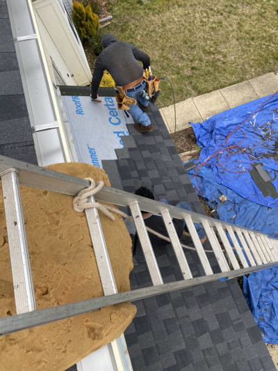 On top of ladder overlooking a contractor inspecting roofing