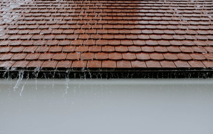 Rain water flowing off of a brown roof top