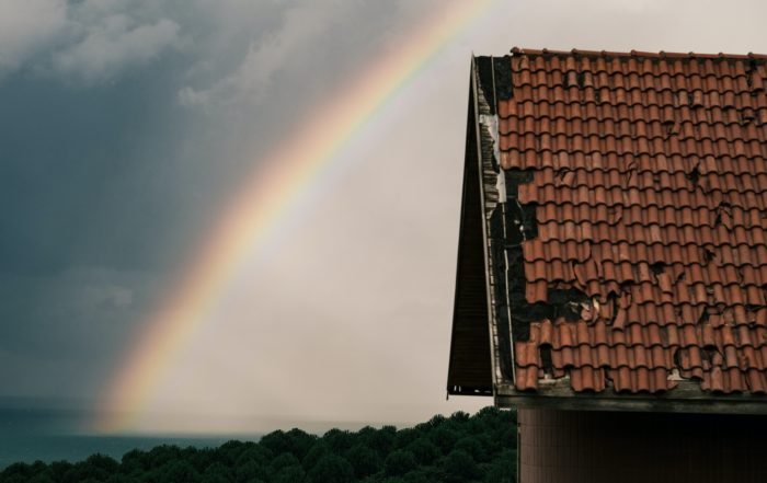 picture of damaged roof with rainbow in background