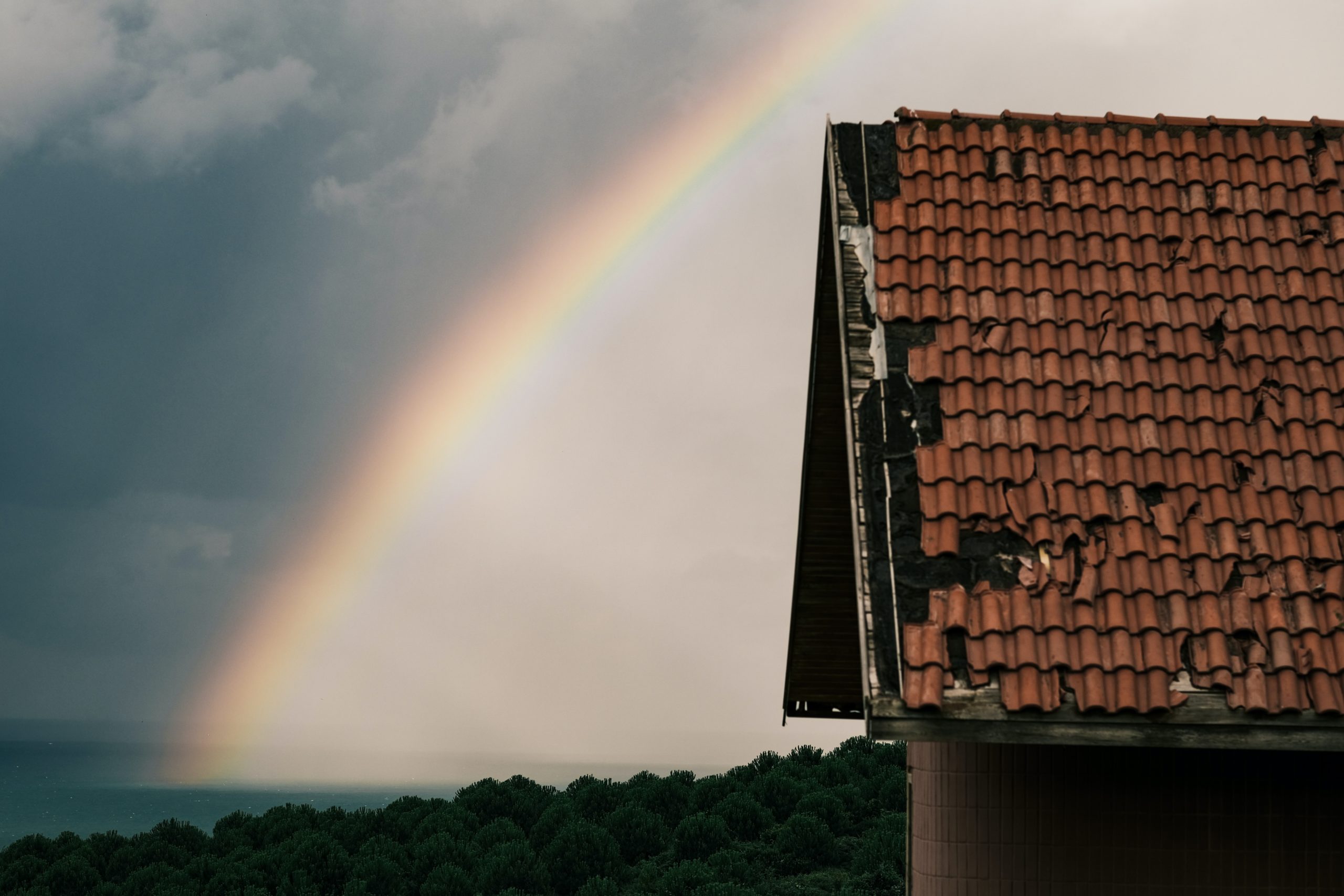 picture of damaged roof with rainbow in background
